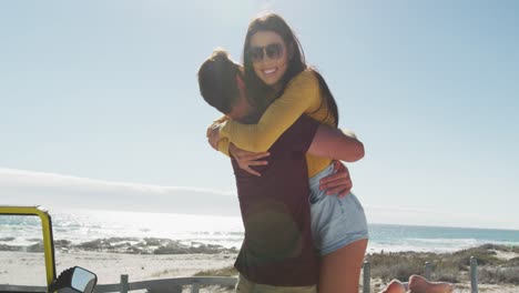 feliz pareja caucásica abrazada cerca de la playa buggy por el mar