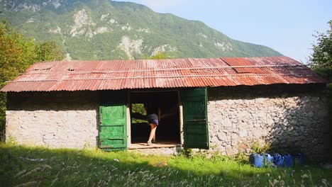 Young-woman-entering-inside-a-mountain-cabin-and-sitting-on-a-hammock