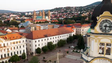 flock of birds flying over szechenyi square with mosque of pasha qasim, city hall and distant view of pecs cathedral in hungary