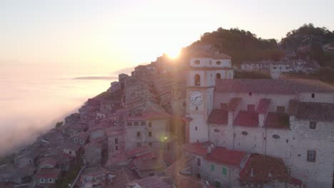 Idyllic-Artena-town-on-hill-slope-with-church-during-bright-sunrise,-aerial