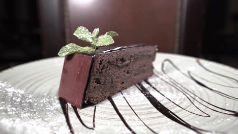 piece of chocolate cake on a beautiful plate spins. restaurant dessert. rotating food. presentation of the dish in cafe