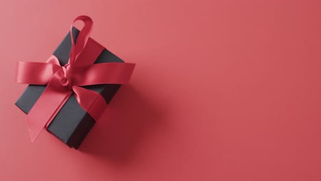 Video-of-gift-box-with-red-ribbon-and-copy-space-over-red-background