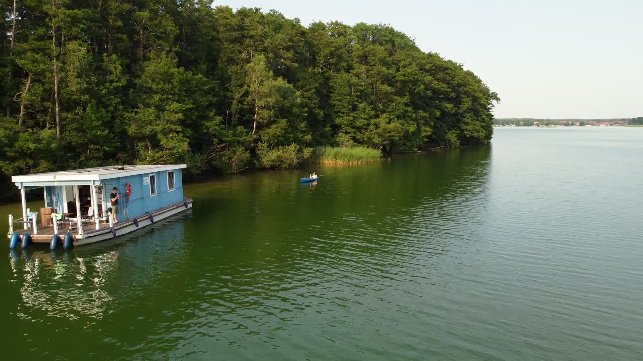 독일 브란덴부르크 의 숲  에 있는 초록색 자연 호수 에 있는 하우스 보트 로 카누 를 타고 가는 사람