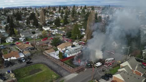 vista aérea de los bomberos rociando agua sobre la casa en llamas con humo denso durante el día