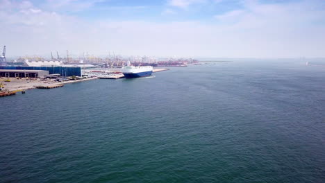 Aerial-view-of-logistics-concept-cargo-ship-sailing-out-to-the-open-sea-leaving-Laem-Chabang-dockyard-in-Chonburi-Province,-Thailand