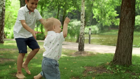 Elder-brother-playing-with-toddler-in-park.-Happy-family-having-picnic-outdoors