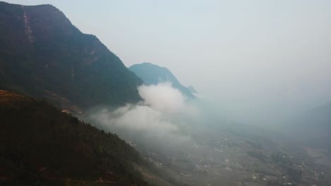 toma aérea de un valle neblinoso, con montañas por encima de las nubes