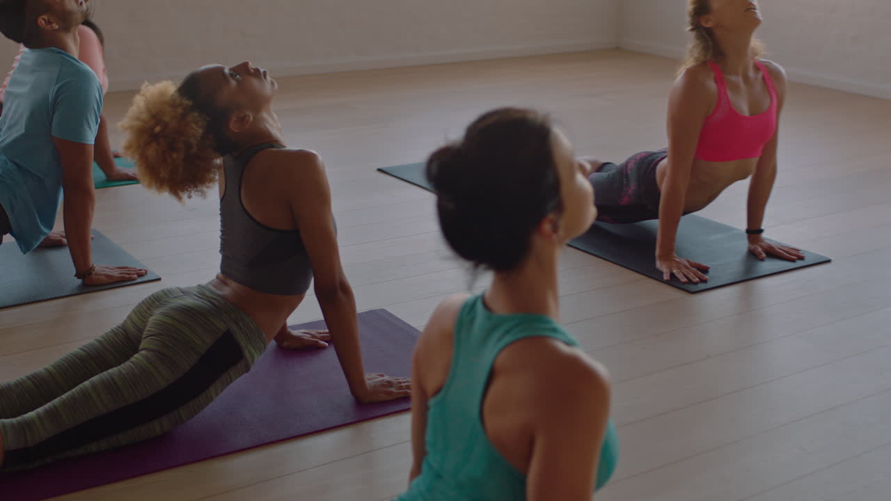 yoga class of young healthy people practicing downward-facing dog pose instructor woman teaching diverse group enjoying fitness lifestyle exercising in studio at sunrise