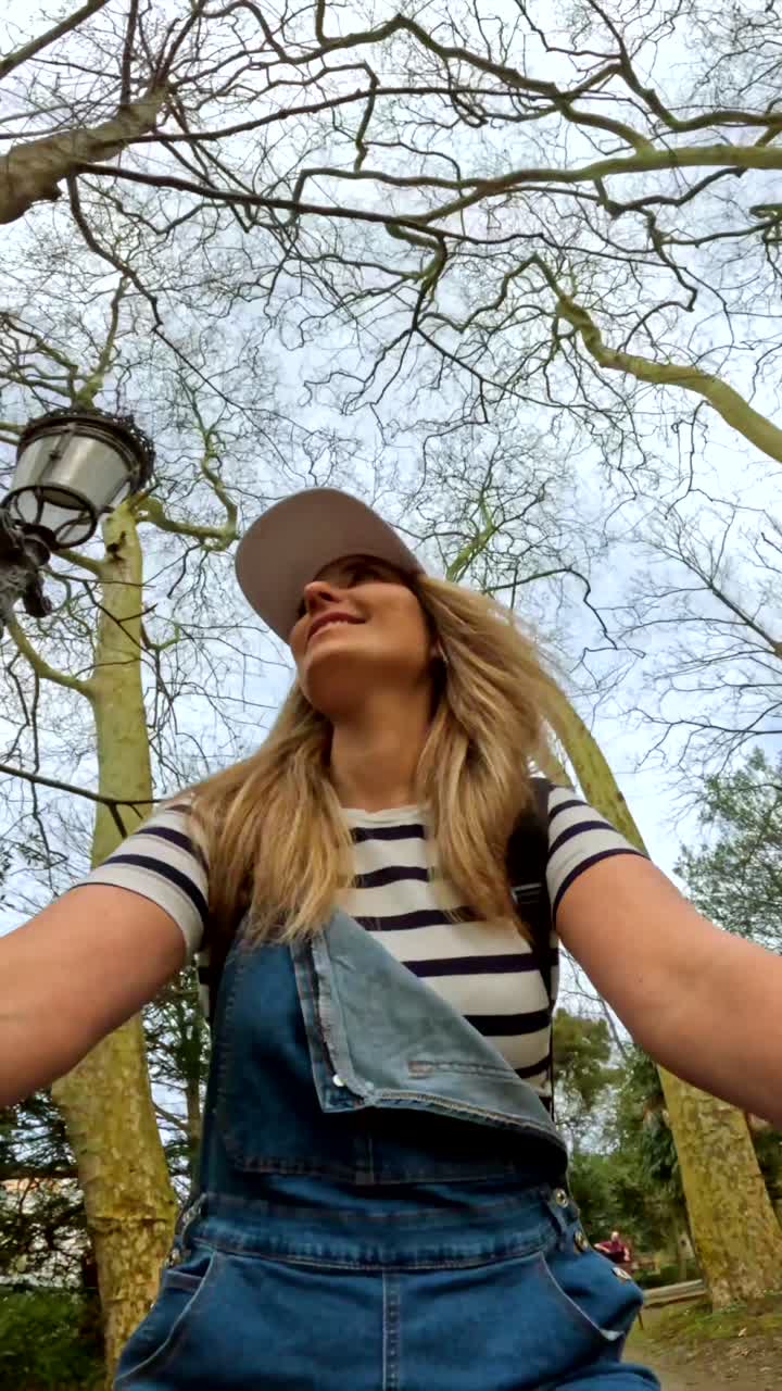 Woman in Overalls Under Bare Trees