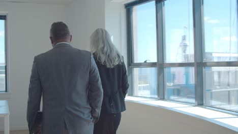 two business colleagues talking while walking to meeting table