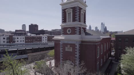 drone panoramizando hacia arriba hasta el campanario de la iglesia - vista de la ciudad de filadelfia en el fondo - 4k