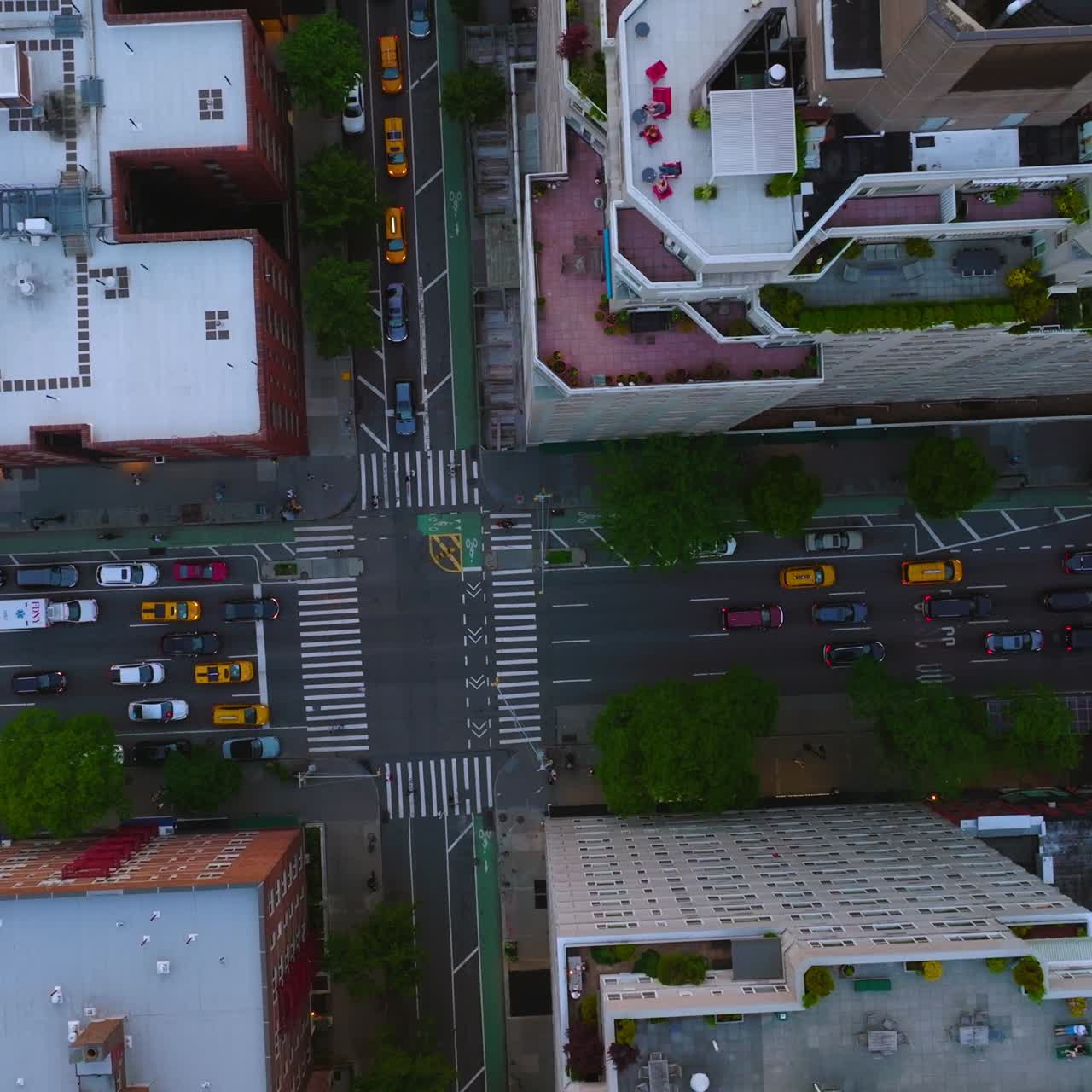 Private cars and yellow taxis ride by the roads of New York. Drone footage over the roofs of buildings in residential area. Top view