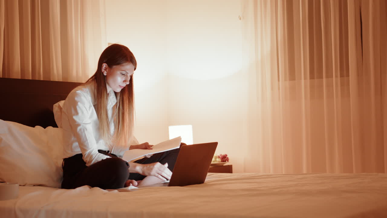 침대에 있는 노트북에서 늦은 밤에 일하는 여자