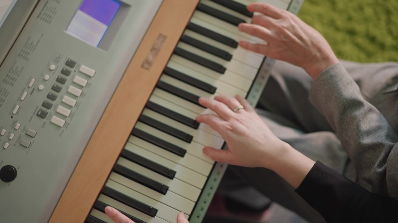 Mani caucasiche riprese dall'alto suonano in duetto sulla tastiera, praticando sincronia e ritmo. Un mentore allena uno studente per un recital in un luminoso soggiorno, con un tempo allegro e una coordinazione vivace, concentrandosi sulla tecnica del polso e delle dita.