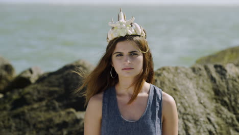 model with mermaid sea shell crown at beach stares at camera, medium