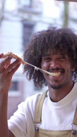happy man enjoying a slice of pizza with stretchy cheese
