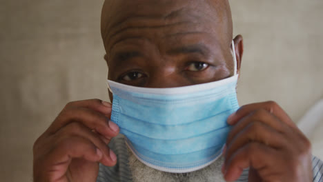 close-up of portrait of african american senior man wearing face mask at home