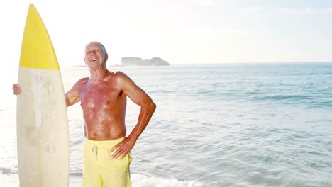 Retired-old-man-holding-surfboard-near-sea