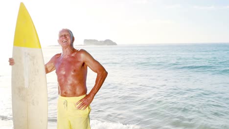 retired old man holding surfboard near sea