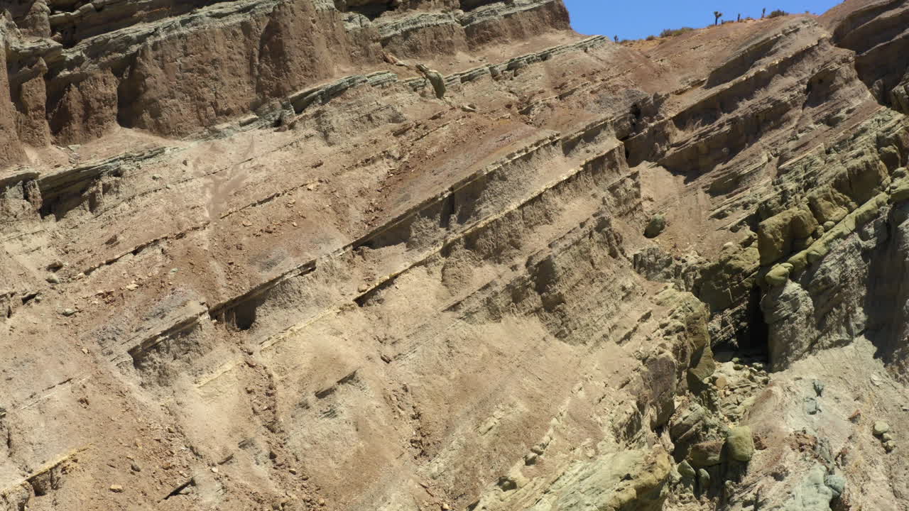 volando hacia arriba y hacia afuera de las formaciones rocosas en capas que forman el valle en la cuenca del arco iris parte del desierto de mojave