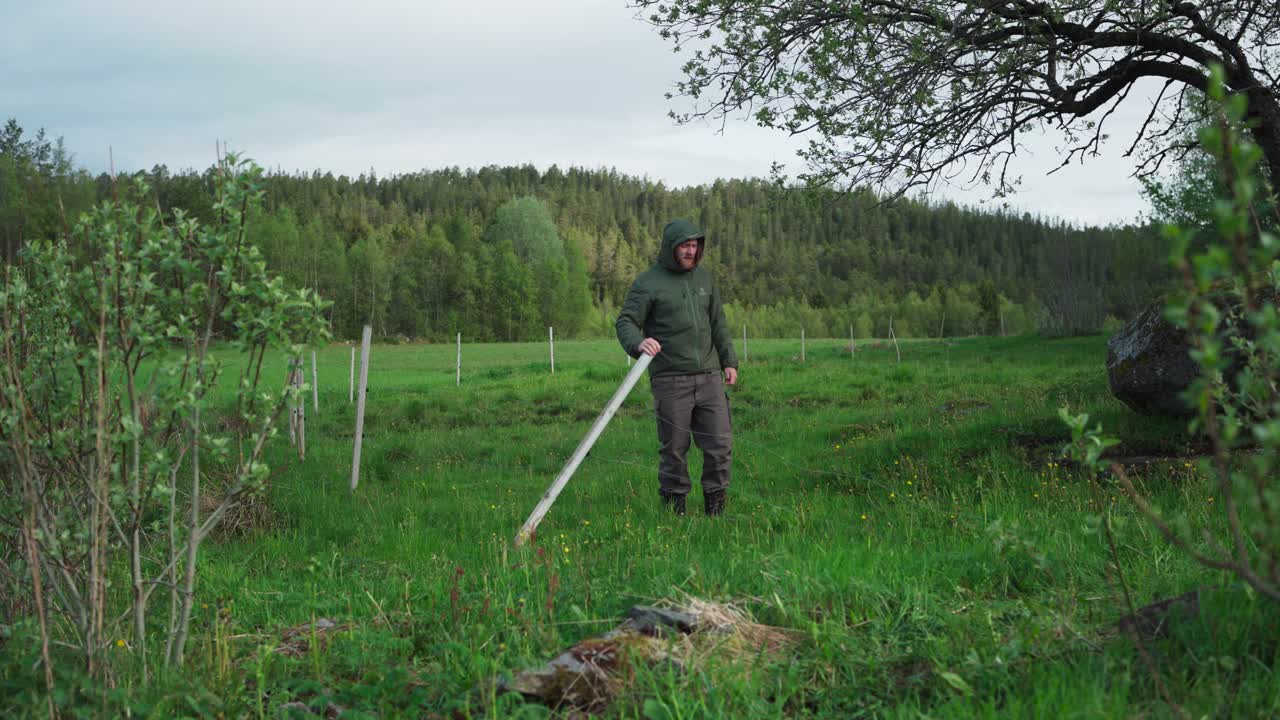 hombre chequeando el poste de valla tropezado en el campo rural