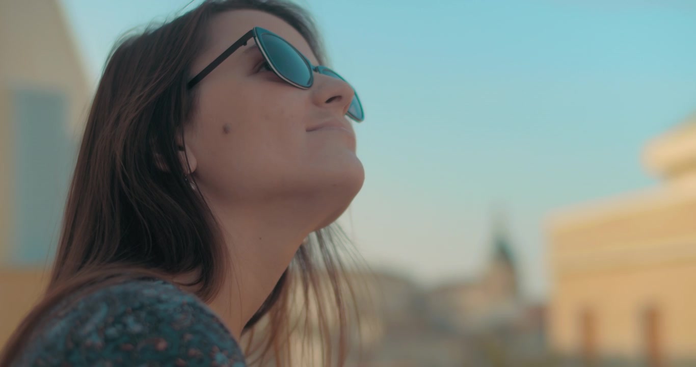 Woman in sunglasses looking up the sky