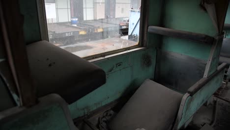 asientos de pasajeros rotos dentro de un tren abandonado con ventana rota