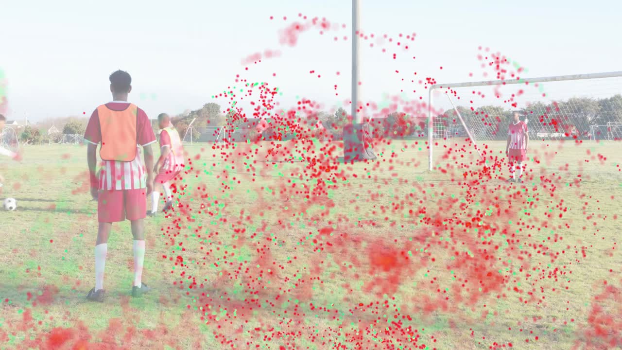 Particle swirl appearing, soccer player in orange bib shifting, watching teammates finish drill