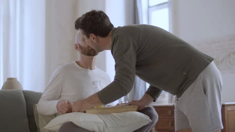 homosexual man bringing breakfast to his partner in bed