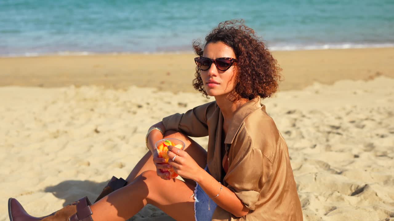 Donna che si rilassa sulla spiaggia con un cocktail