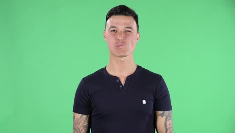 retrato de un joven guapo mirando directamente sonriendo y mostrando un gesto de corazón y un beso en el aire. pantalla verde