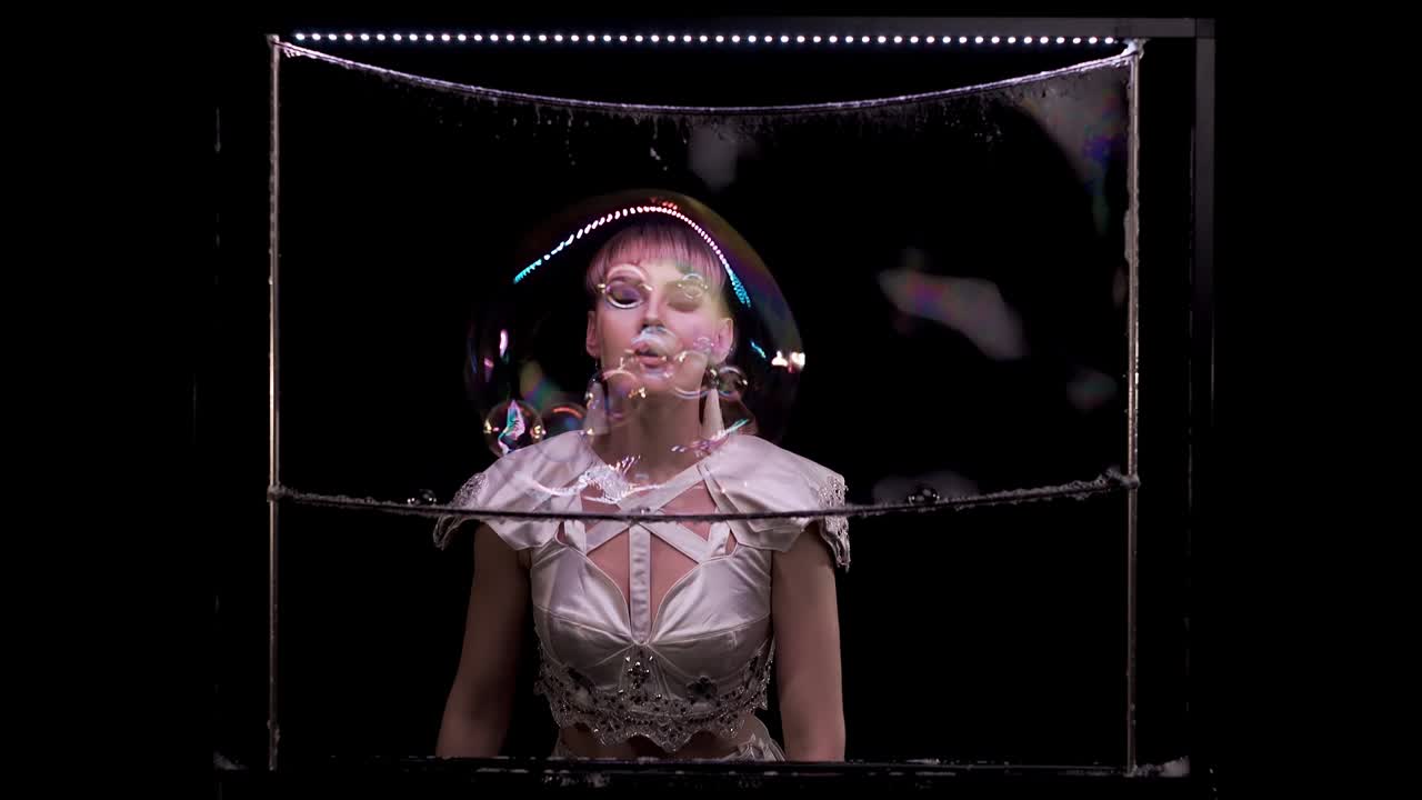 아름다운 소녀는 비누 거품으로 트릭을합니다. 그녀는 비누 스크린에 비누 버블을 불어