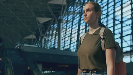 Woman-traveler-with-a-backpack-at-the-airport-looking-at-the-scoreboard-departures-looking-for-your-flight