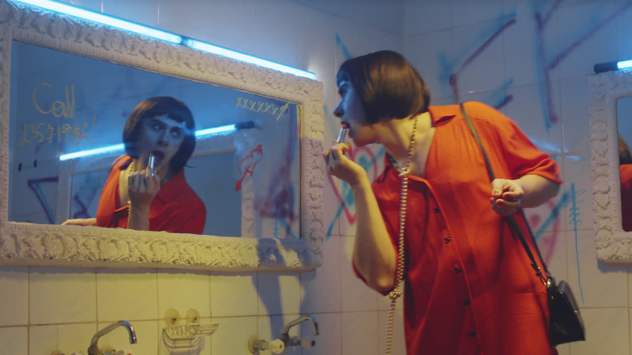 Uomo transgender che balla e si mette il rossetto nel bagno di una discoteca