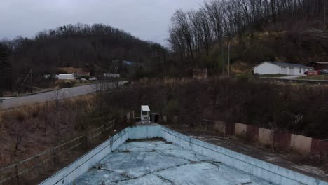 aerial drone footage pushing in over an overgrown wave pool in an abandoned water park