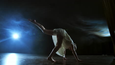 Una-Mujer-De-Danza-Moderna-Con-Un-Vestido-Blanco-Baila-Un-Ballet-Moderno-Salta-Al-Escenario-Con-Humo-En-Los-Focos-Azules.