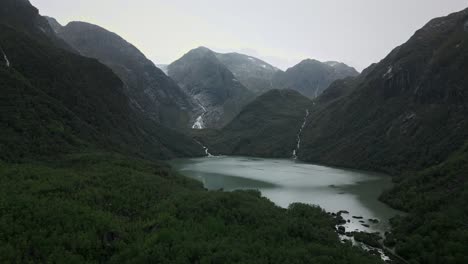 Drone-flies-into-a-valley-surrounded-by-mountains-and-the-mountains-of-Norway