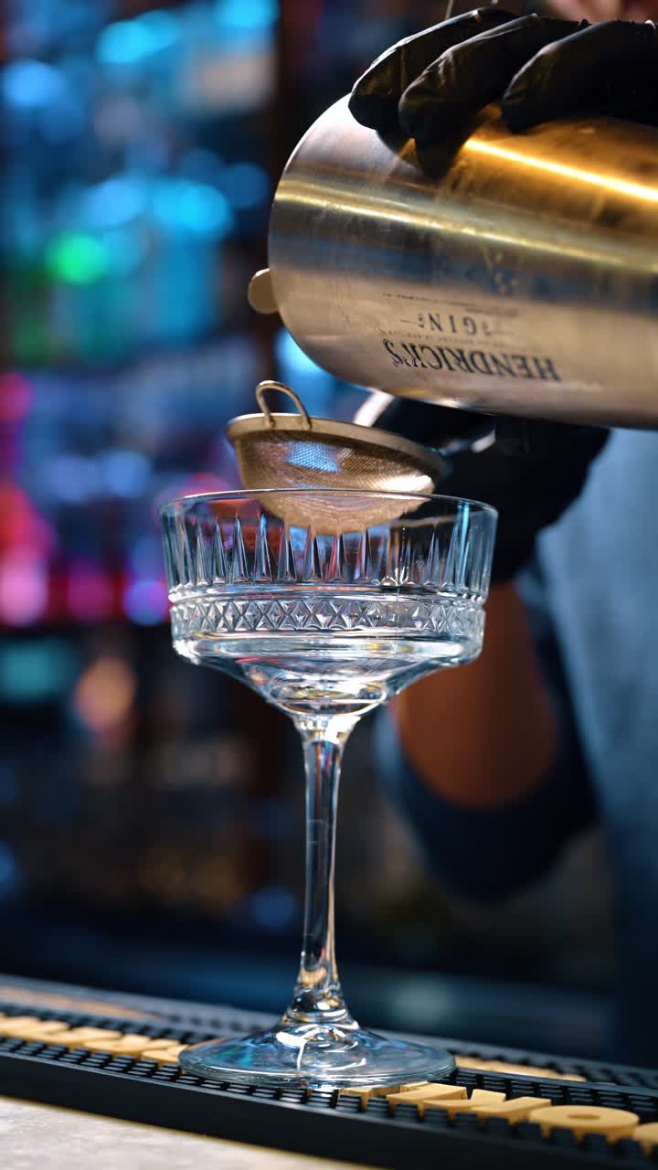 New York, USA, 15 aprile 2026: Bicchiere da cocktail vuoto e colino pronti per versare la bevanda. Primo piano di un bicchiere coupe di cristallo su tappetino da bar con colino in metallo e shaker sopra