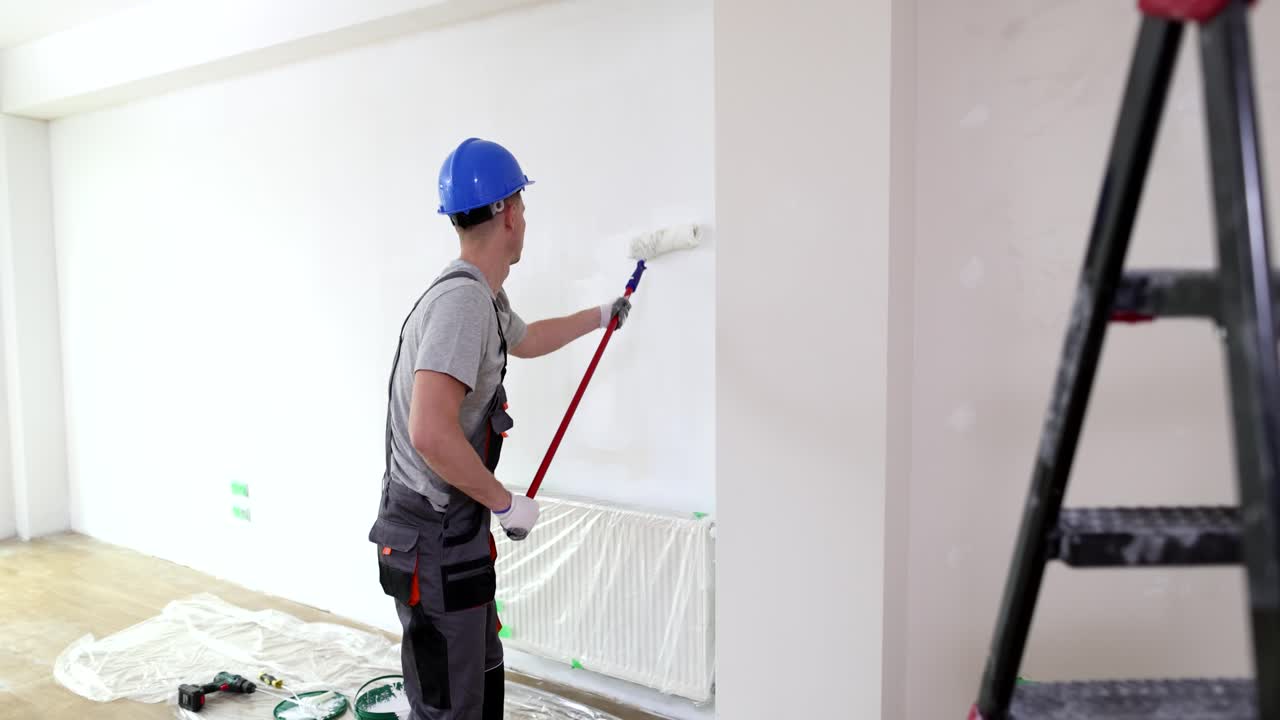 Man painting a white wall in a room during home renovation