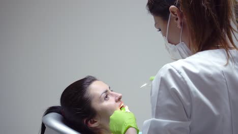 stomatologist using water syringe to clean the patient's mouth. female patient with open mouth. dentist using saliva ejector or dental pump to evacuate saliva. shot in 4k