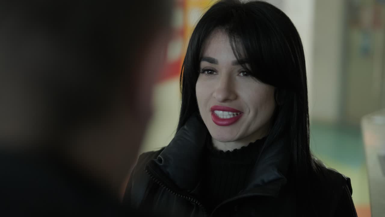 검은색 의상을 입은 전문적인 여성 관리자가 사무실을 걸어다니며 동료들과 상호 작용하며 문서와 노트북을 들고 리더십과 전문성을 보여주고 있습니다.