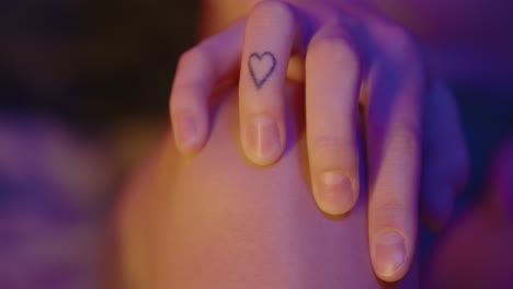 mujer joven tiene un corazón tatuado en su dedo