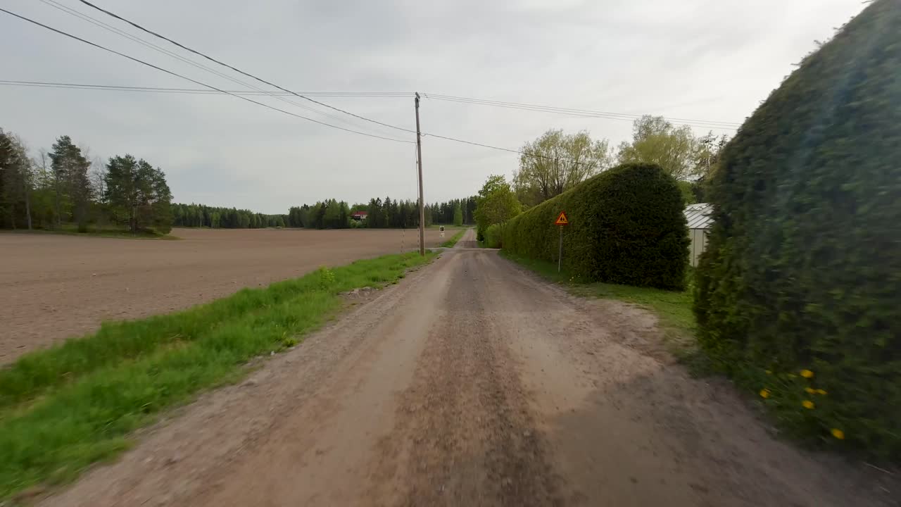 L'auto viaggia lungo una strada rurale sterrata, mentre attraversa il villaggio.