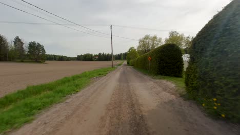 the car travels along a rural road, unpaved, as it passes through the village