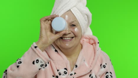 elderly grandmother in bathrobe. old senior woman with moisturizing cream jar