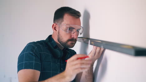 hombre en gafas utiliza nivel moderno para comprobar la pared en la habitación