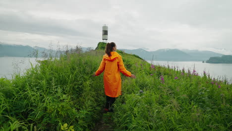 woman in an orange raincoat hiking on a coastal path