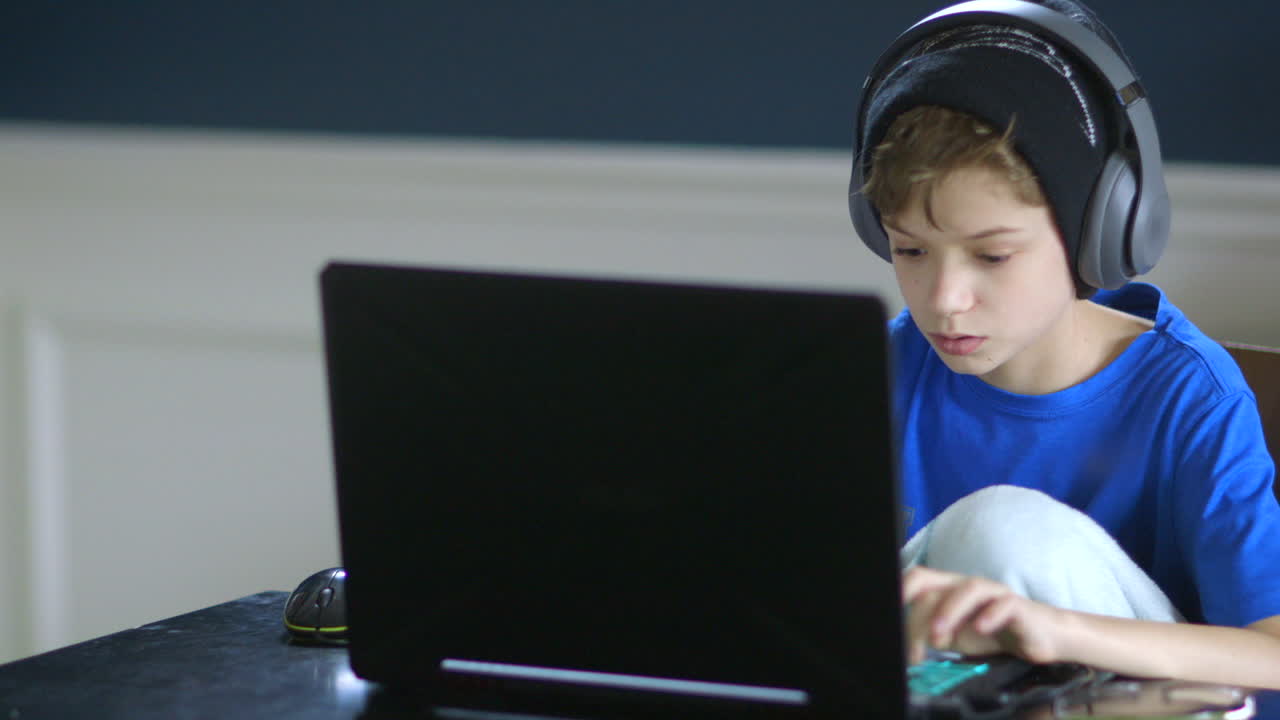 niño jugando en su computadora portátil y usando auriculares