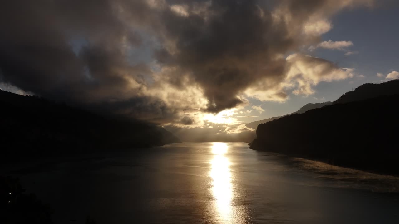 Dramatic sunset over Walensee, golden reflection on water, moody clouds, Amden, Switzerland