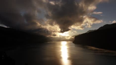 dramatic sunset over walensee, golden reflection on water, moody clouds, amden, switzerland